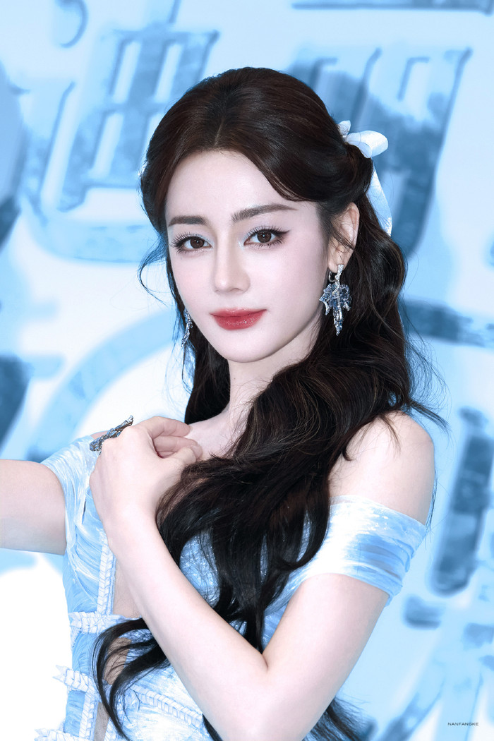 Địch Lệ Nhiệt Ba liên tục lấy tay che trước ngực vì diện váy xẻ sâu. Ảnh: Weibo