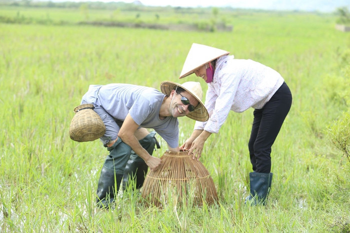 Du khách thích thú trải nghiệm hoạt động đồng quê với người dân Ninh Bình. Ảnh: QĐND