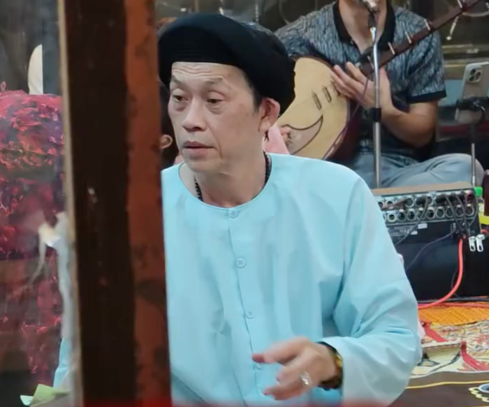 Trong đoạn clip được chia sẻ, nam nghệ sĩ diện áo màu xanh nhạt, đội mũ đen và ngồi giữa không gian sinh hoạt của lễ hội. (Ảnh: Vẻ Đẹp Huế)