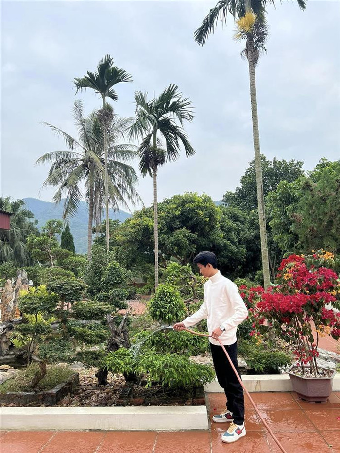Mạc Văn Khoa giúp bố mẹ chăm sóc cây cảnh xung quanh nhà.