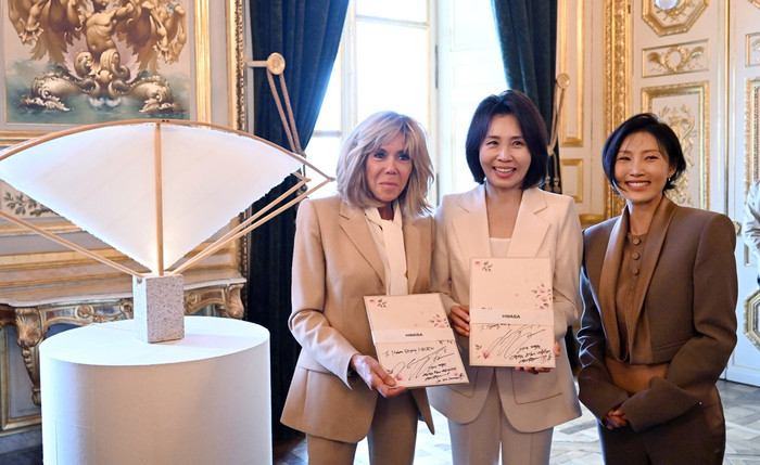 Từ trái sang: Đệ nhất phu nhân Pháp Brigitte Macron, Đệ nhất phu nhân Hàn Quốc Kim Hea Kyung và Hwasa chụp ảnh cùng những album đựng trong hộp chữ Hán do nữ ca sĩ tặng trong triển lãm đặc biệt “Hanjimania” tại khách sạn Hotel de la Marine ở Paris hôm thứ Ba. (Yonhap)
