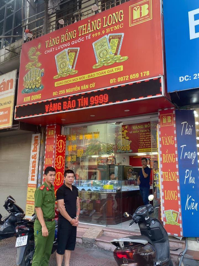 Hải được công an áp giải về tiệm vàng nơi xảy ra sự việc.