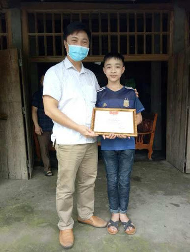 Ban giám hiệu trường Phổ thông dân tộc nội trú THCS huyện Hàm Yên trao giấy khen cho Đội viên Lý Hùng Vương, Chi đội 7A về hành động ủng hộ tiền cho việc phòng chống dịch COVID - 19.