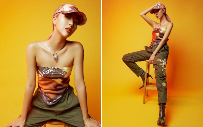 Quỳnh Anh Shyn quấn khăn hình áo ống, mặc cùng quần dài màu xanh rêu, đội nón lưỡi trai và mang giày boots đế nhọn cá tính. Cô sử dụng thêm phụ kiện vòng cổ có mặt đeo hình chú bọ cạp bằng bạc sang chảnh. 