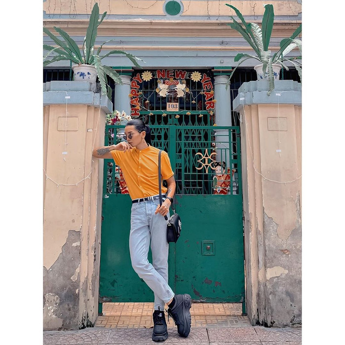 Bb Trần chọn trang phục Theo phong cách nam tính, lịch lãm. Áo sơ-mi tông màu vàng đất được anh chàng mix hài hoà cùng quần jeans xanh. Đôi giày và túi đen cùng tông góp phần hoàn thiện set đồ. 