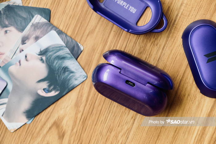 Hộp đựng kiêm sạc pin cho tai có lớp vỏ ngoài màu tím bóng bẩy.