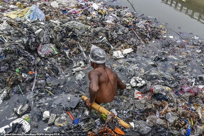 Những người làm công việc dọn rác chẳng có vật dụng bảo hộ. Họ chỉ đội túi ni lông lên đầu và mình trần ngâm người dưới con kênh ken đặc rác thải.