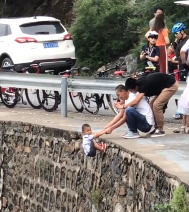 Người cha liều lĩnh chỉ nắm hai tay con trai đưa bên rìa đường núi dốc đứng
