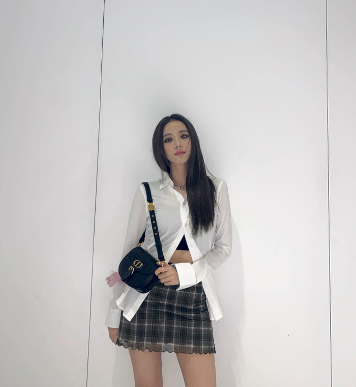 Jisoo diện áo sơ mi bung nút hững hờ mix cùng chân váy caro, bên trong cô cẩn thận bằng cách mặc thêm một áo quây đen bên trong