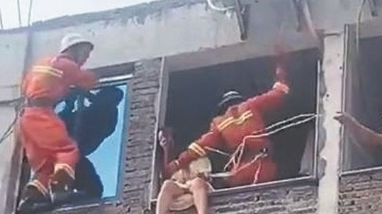 Lính cứu hỏa nhảy sang, đưa người phụ nữ vào bên trong an toàn. 