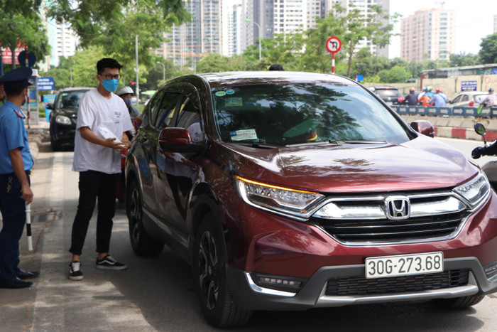 Từng dòng xe ô tô nối đuôi nhau, lực lượng bảo vệ đứng hướng dẫn, đảm bảo an ninh.