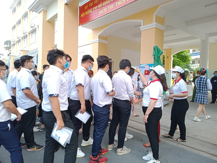 Các sĩ tử xếp hàng chờ đo thân nhiệt để được vào trong tại điểm thi trường THCS Đoàn Thị Điểm