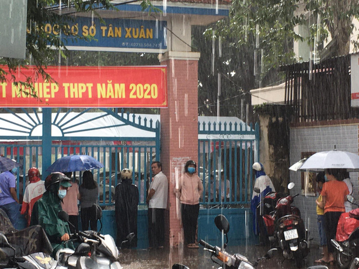 Các bậc phụ huynh đợi con bên ngoài cổng trường dưới cơn mưa to