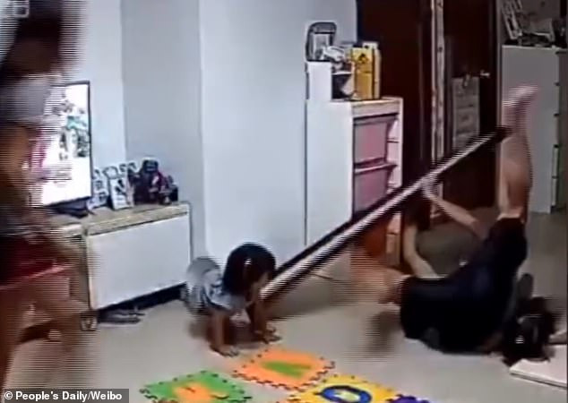 Vừa dùng cả hai tay đỡ lấy gương, anh vừa lấy thân mình che chắn cho cô con gái nhỏ sau lưng.