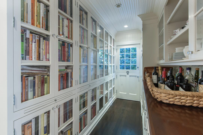 Một góc hành lang của căn biệt thự nổi bật với chiếc tủ sách âm tường cỡ lớn được sơn trắng, bên phía đối diện là chiếc tủ đụng dụng cụ ăn uống và một rổ rượu vang. (Ảnh: Realtor)