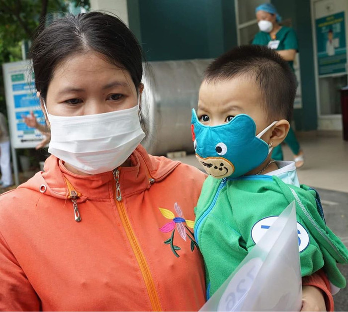 Bé gái 1 tuổi được mẹ bế trong ngày ra viện.