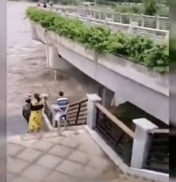Sông Mân Giang chảy siết, cuốn trôi một người đàn ông đang đứng chụp ảnh. 