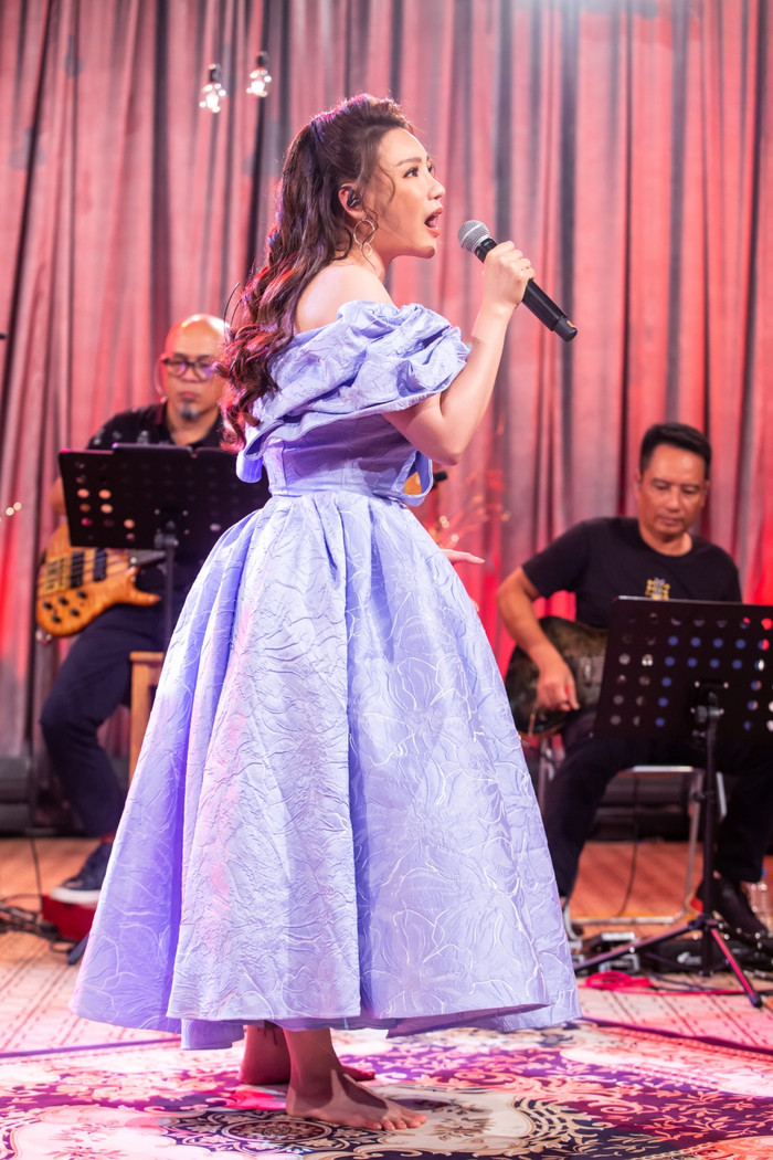 Vì lâu ngày không đứng hát lâu, cô xin tháo giày cao gót để hát chỗ thoải mái.