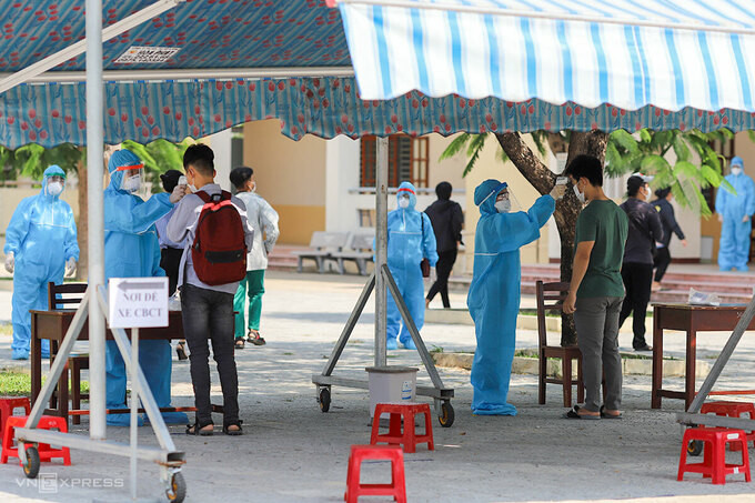 Thí sinh được đo thân nhiệt, thay khẩu trang trước khi vào phòng thi ở trường THPT Võ Chí Công. Ảnh: Nguyễn Đông/VnExpress