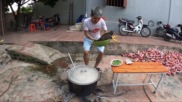 Nam vlogger đã trực tiếp bắt gà và cho nguyên con gà chưa được sơ chế vào nồi cháo đang sôi. (Ảnh: Hưng Troll)