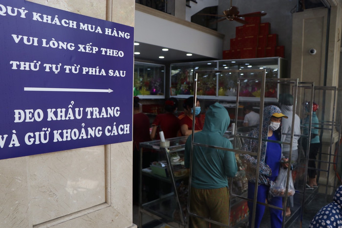 Trước cửa hàng đặt biển thông báo khách xếp hàng theo thứ tự, đeo khẩu trang và giữ khoảng cách.