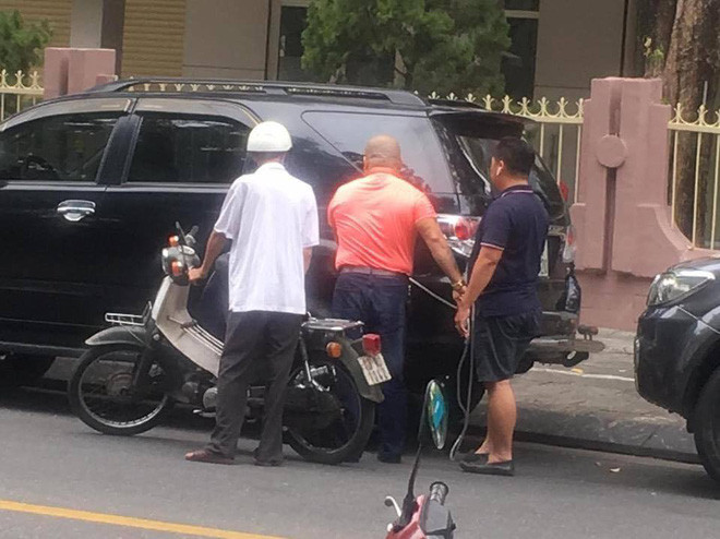 Phát hiện xe máy của cụ ông (áo trắng) hết xăng, 2 người đàn ông đã tấp ô tô vào lề rồi rút xăng cho ông cụ. 