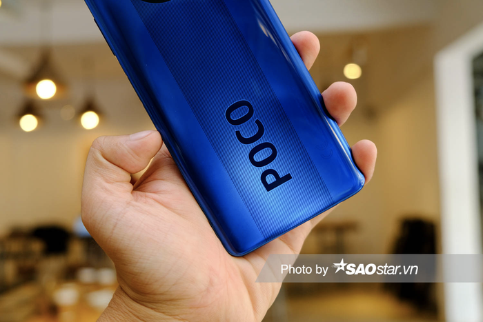 Về thiết kế, POCO X3 NFC có mặt lưng không quá cầu kỳ nhưng vẫn tạo được điểm nhấn với các họa tiết vân giữa mặt lưng cùng logo POCO cỡ lơn. Mặt lưng cùng các họa tiết đi kèm cho hiệu ứng chuyển màu sắc mỗi khi người dùng thay đổi góc nhìn.