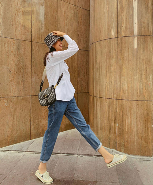 Áo sơ mi cùng quần jeans luôn là set đồ cơ bản, hãy nâng tầm nó bằng cách mix cùng phụ kiện đắt giá, giống túi và nón của thương hiệu Dior trong set đồ này. 