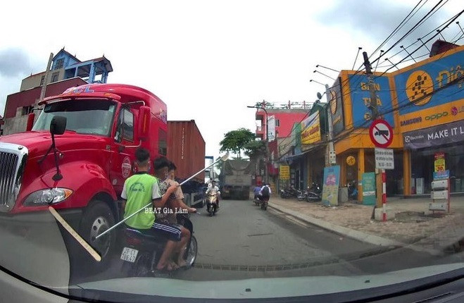 Hình ảnh 3 thanh niên cầm theo dao phóng lợn di chuyển trên đường