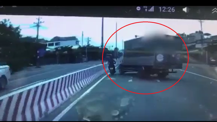Hành động bất ngờ tạt đầu, ép xe máy vào dãy phân cách của tài xế ô tô tải suýt gây nguy hiểm cho nam thanh niên điều khiển. Ảnh cắt từ clip