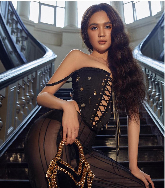 Thiết kế áo corset nâng vòng 1 ngồn ngộn của Ngọc Trinh khiến ai cũng đỏ mặt, cô mix cùng quần đen xuyên thấu mong manh đi kèm là phụ kiện túi mạ vàng xiềng xích 