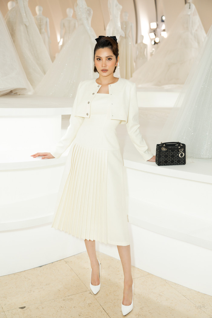 Hoa hậu Diệu Linh đẹp tao nhã, rạng ngời trong sắc trắng tinh khôi. Chiếc túi Dior đắt giá được sử dụng làm điểm nhấn, vừa tăng độ thời thượng. 