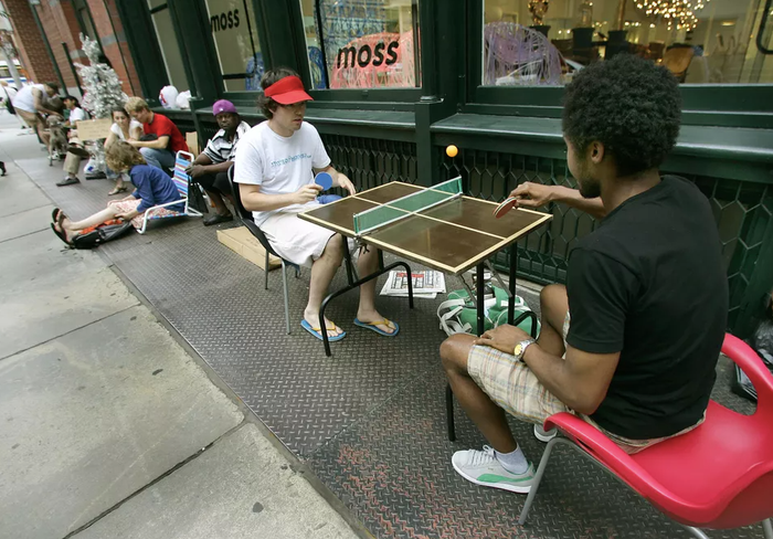 Hai người hâm mộ Apple này mang hẳn bàn bóng bàn mini tới nơi xếp hàng mua iPhone. Ảnh: Getty