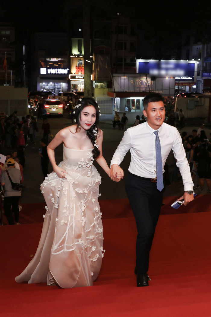Vợ chồng Công Vinh - Thủy Tiên lần đầu sánh đôi trên thảm đỏ của Lễ trao giải Làn sóng xanh 2018. Xuất hiện trong bộ đầm họa tiết hoa mai anh đào, Thủy Tiên khoe vẻ đẹp dịu dàng, đằm thắm. Công Vinh đi trước, dắt tay vợ theo sau và luôn cẩn thận quan sát khi Thủy Tiên bước đi cùng chiếc đầm dài.