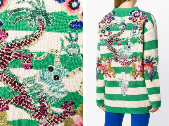 Thiết kể có chất vải len dệt sọc ngang xanh, phần vai và sau được trang trí họa tiết họa tiết thêu hình chim công nhiều màu sặc sỡ làm điểm nhấn.  