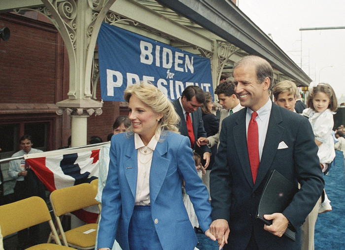 Tháng 6/1987, ông Joe Biden  tay trong tay bên vợ sau khi tuyên bố tranh cử tổng thống ở Wilimington, Delaware, Mỹ trong bộ suit xanh đen nhấn nhá cà vạt đỏ