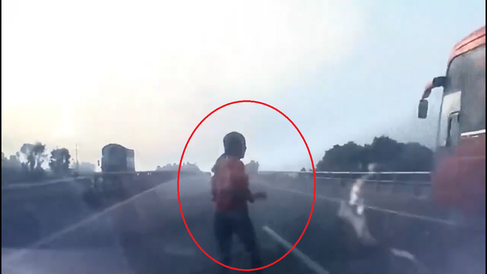 Bất chấp nguy hiểm, người phụ nữ này vẫn cố băng qua đường cao tốc để bắt xe khách. Ảnh cắt từ clip