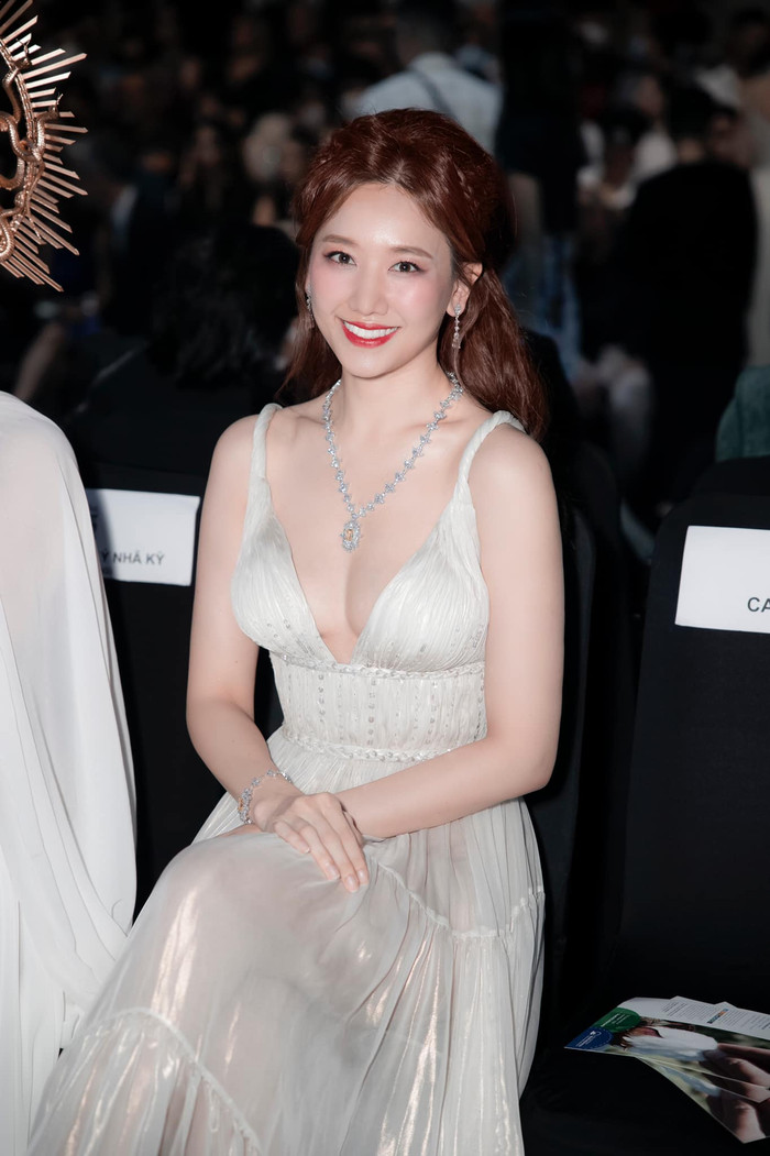 Ca sĩ Hari Won thu hút ánh nhìn của đám đông trước nhan sắc tỏa sáng với bộ trang sức kim cương sang trọng. Bộ trang phục màu trắng lấp lánh với phần cổ xẻ sâu và xếp nếp tỉ mỉ mang lại vẻ kiêu sa đầy lộng lẫy. Thiết kế với độ dài phủ gót cùng đường xếp ly khéo léo tôn lên vòng eo thon gọn và những bước đi thướt tha, kiều diễm trên thảm đỏ.