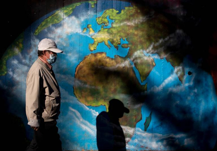 Một người đàn ông đeo khẩu trang bước ngang qua bức vẽ graffiti phỏng theo bản đồ thế giới ở khu phố Orcasitas, thủ đô Madrid (Tây Ban Nha) hôm 28/9.