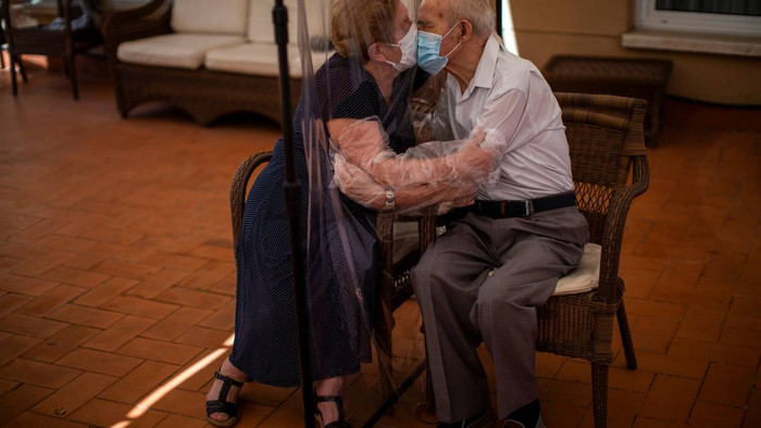 Bà Agustina Canamero (81 tuổi) và ông Pascual Perez (84 tuổi) ôm hôn nhau qua tấm chắn nhựa tránh lây lan COVID-19 tại một viện dưỡng lão ở Barcelona, ​​Tây Ban Nha hôm 22/6.