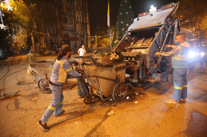 Công nhân dầm giá lạnh dọn dẹp rác trong đêm.