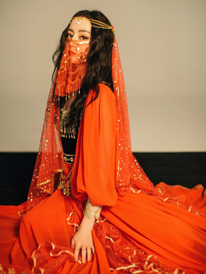 Người đẹp diện trang phục đỏ rực thêm thắt những phụ kiện mạ vàng từ vòng gắn tóc cho đến body chain lủng lẳng trên thân váy