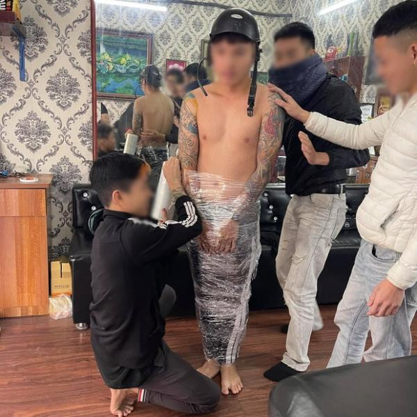 Nam thanh niên bị bắt cởi trần, quấn nilon khắp người vì quỵt tiền xăm. 
