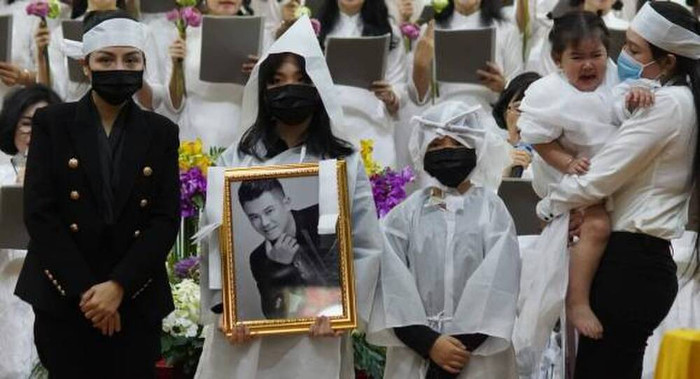 Con gái lớn của Vân Quang Long cầm di ảnh cha trong tang lễ tại Việt Nam.