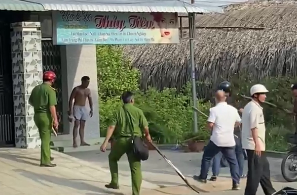 Đối tượng cầm búa cố thủ đe dọa cảnh sát. Ảnh Tuổi Trẻ