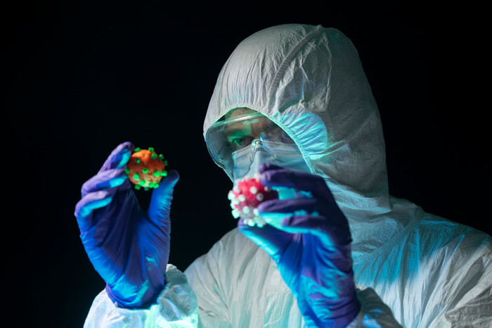 Nhà khoa học trong bộ đồ bảo hộ so sánh hai biến thể virus SARS-CoV-2 có màu sắc khác nhau trên tay. (Ảnh: Aitor Diago | Moment | Getty Images)