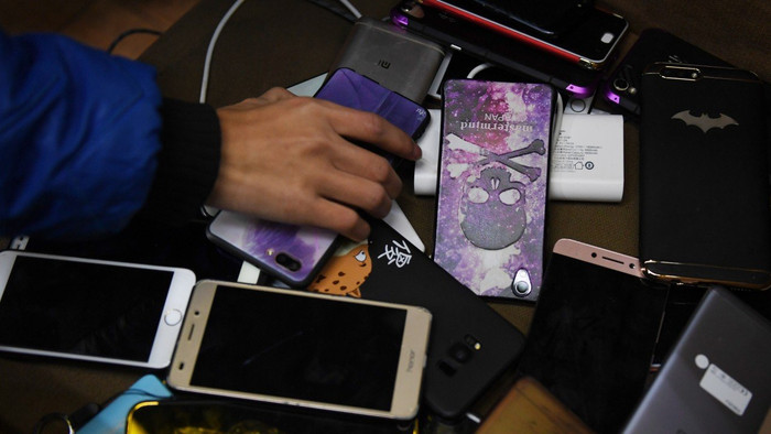 Một sinh viên lấy lại điện thoại di động của mình sau khi hoàn thành bài thi tại một trường kỹ thuật ở Tế Nam, Trung Quốc. Bắt đầu từ tuần này, học sinh tại tất cả các trường học ở Trung Quốc phải nộp bài trong giờ học và cần được phép của phụ huynh và nhà trường để mang điện thoại đến trường. (Ảnh: AFP)