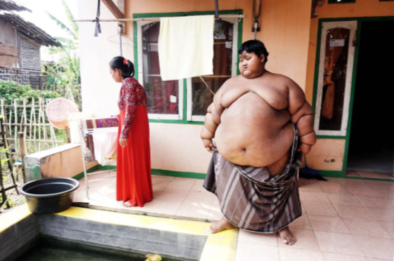 Hàng ngày, bé trai người Indonesia chỉ quấn quanh người một chiếc khăn to, bởi chẳng có quần áo nào vừa với em cả. 