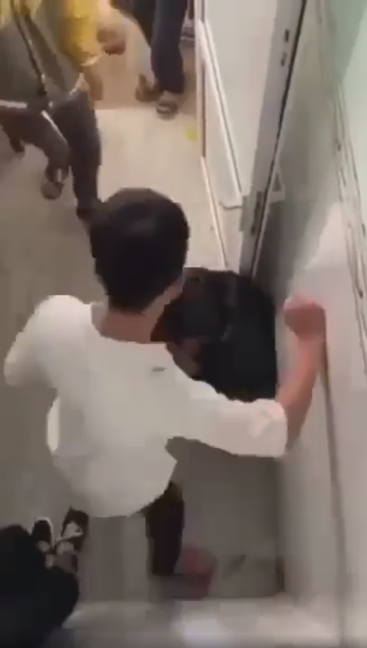 Nam sinh ôm đầu, ngồi bệt xuống sàn khi bị đánh hội đồng. Ảnh cắt từ clip 