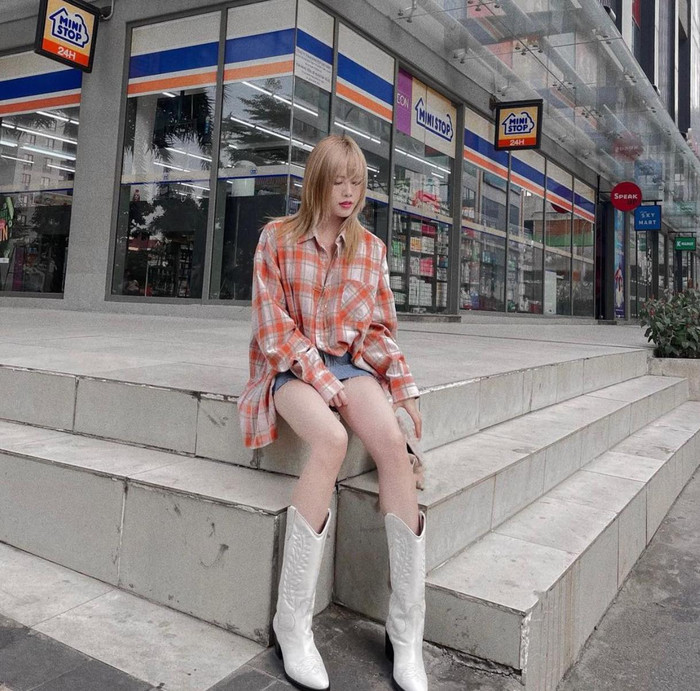 Áo sơ mi kẻ sọc ca rô màu cam oversized được nữ ca sĩ kết hợp ngẫu hứng với boots cao bồi và váy ngắn khoe được chân thon 
